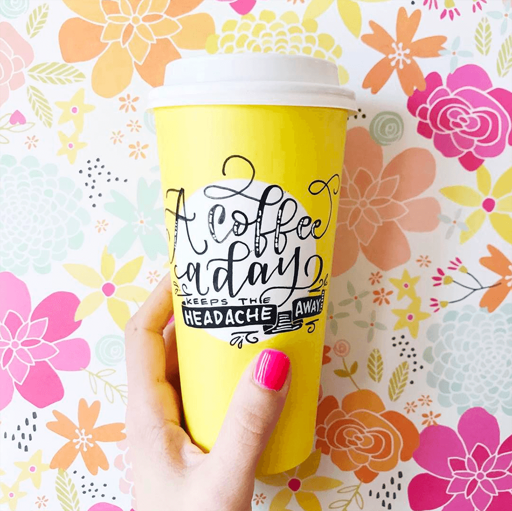 Yellow hand lettered coffee cup with flower background